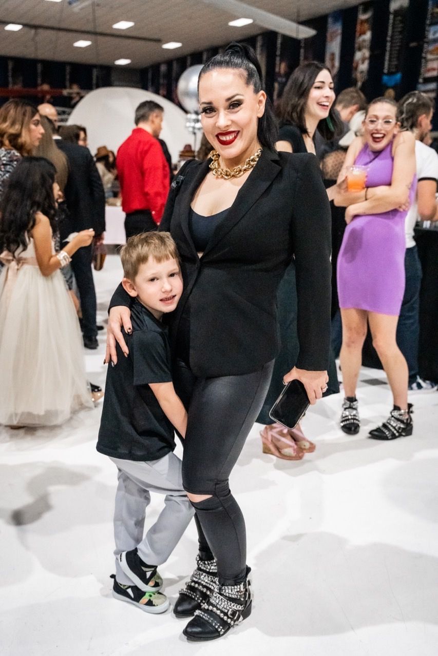 A woman is holding a little boy in her arms while standing in front of a crowd of people.