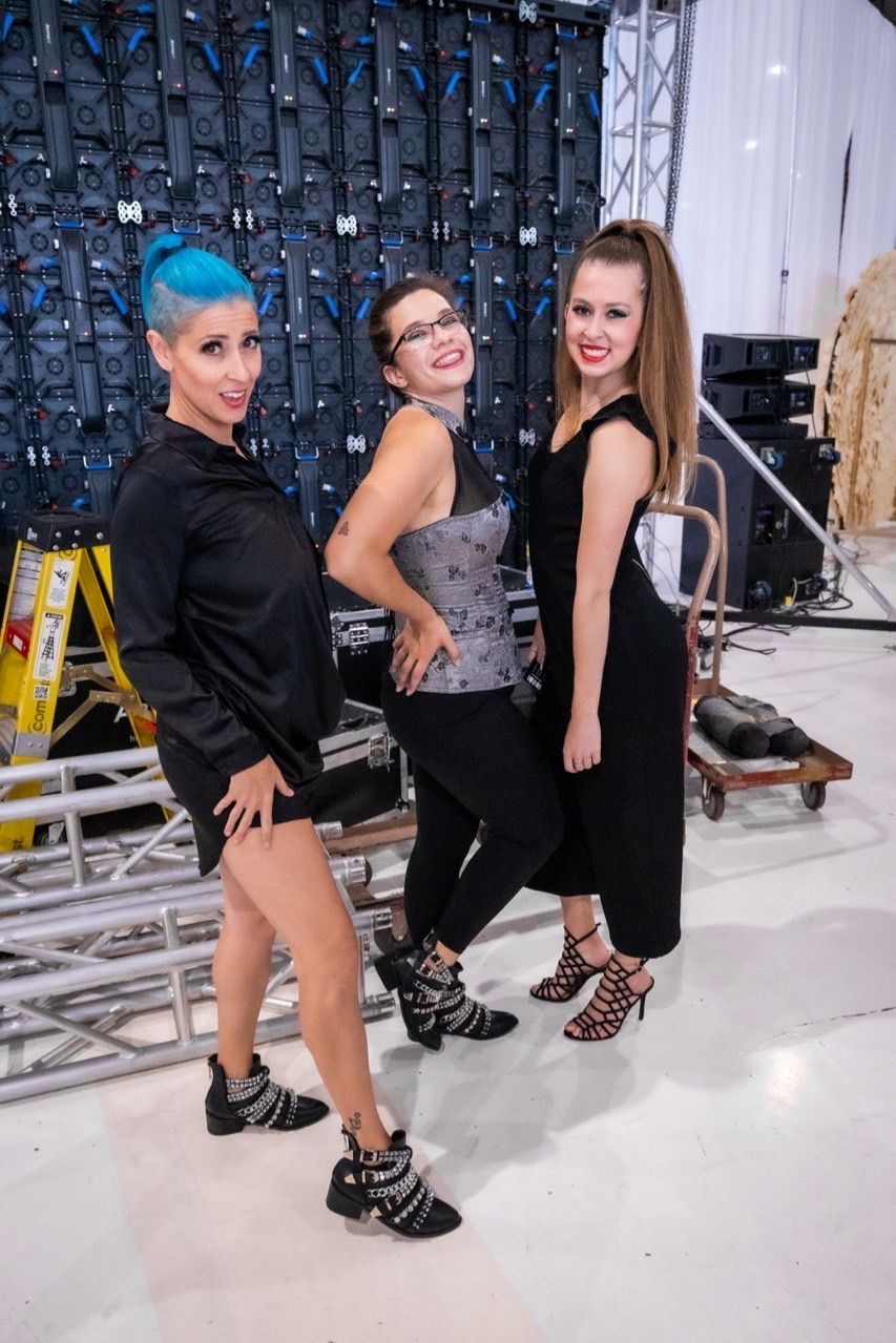 Three women are standing next to each other in a room.