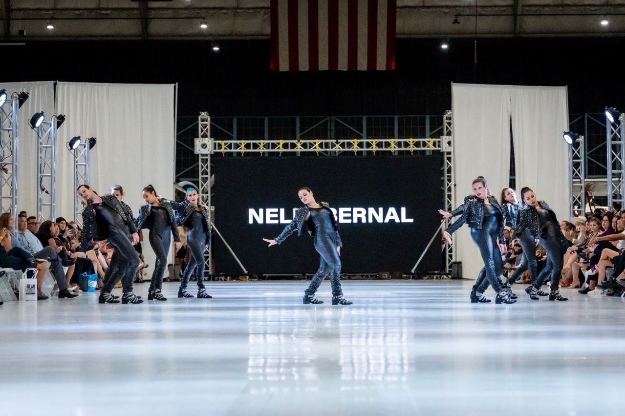 A group of people are dancing on a stage at a fashion show.