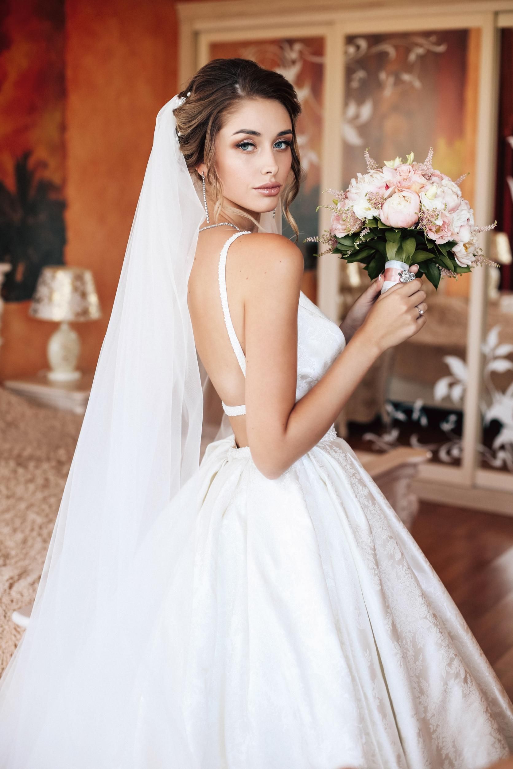 A bride in a wedding dress is holding a bouquet of flowers.