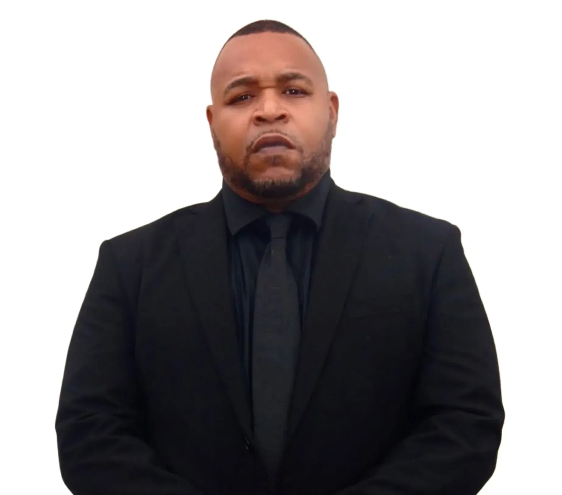 Man wearing a black suit and tie, looking directly at the camera.