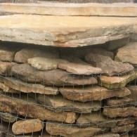 Stacked flat stones behind wire mesh in a rustic wall or enclosure