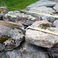 Large mossy rocks arranged in a garden beside a stone walkway