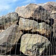 Rocks stacked behind a wire fence under a blue sky