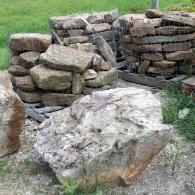 Stacked stone blocks and a large boulder on a grassy outdoor ground