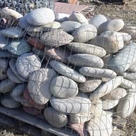 Stacked gray sandbags on pallets outdoors at a construction site