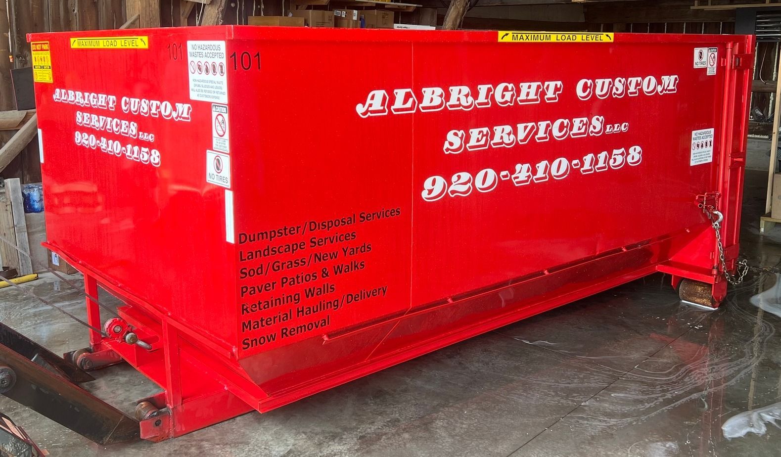 Green industrial dumpster on wheels, outdoors.