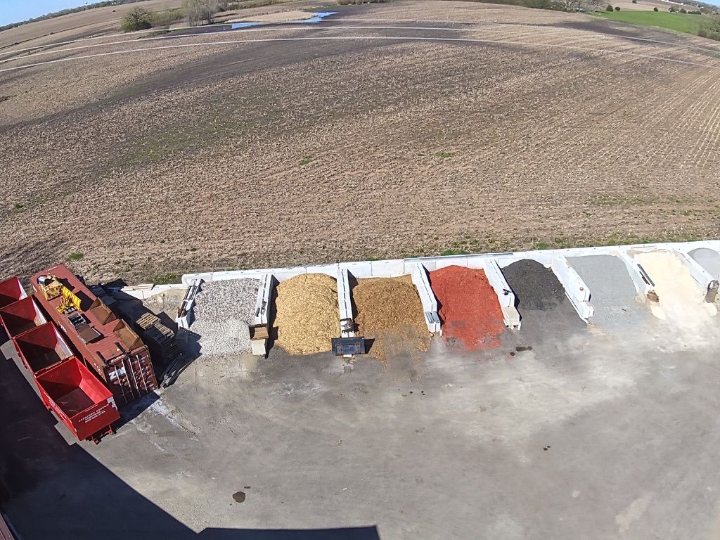 Overhead view of various landscaping materials in bins on a concrete surface next to a field. Overhead view of various landscaping materials in bins on a concrete surface next to a field.