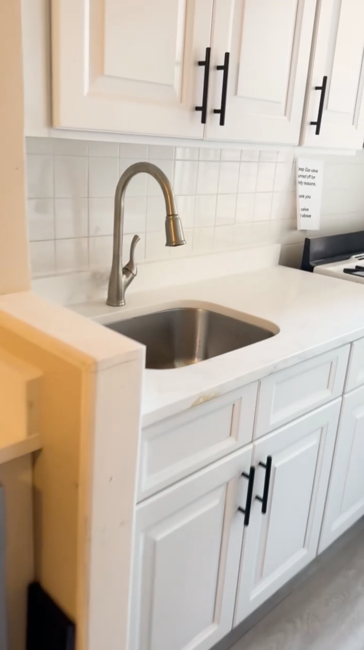 A kitchen with white cabinets and a stainless steel sink.