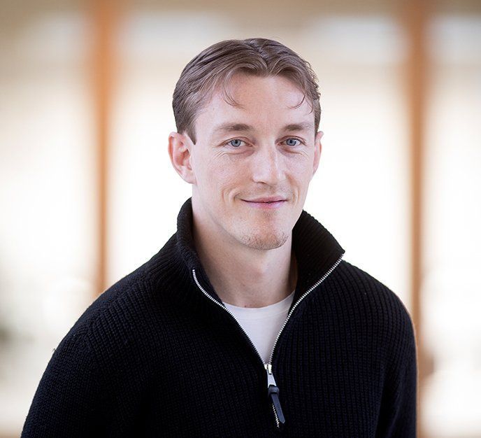 En mand iført en sort sweater smiler til kameraet