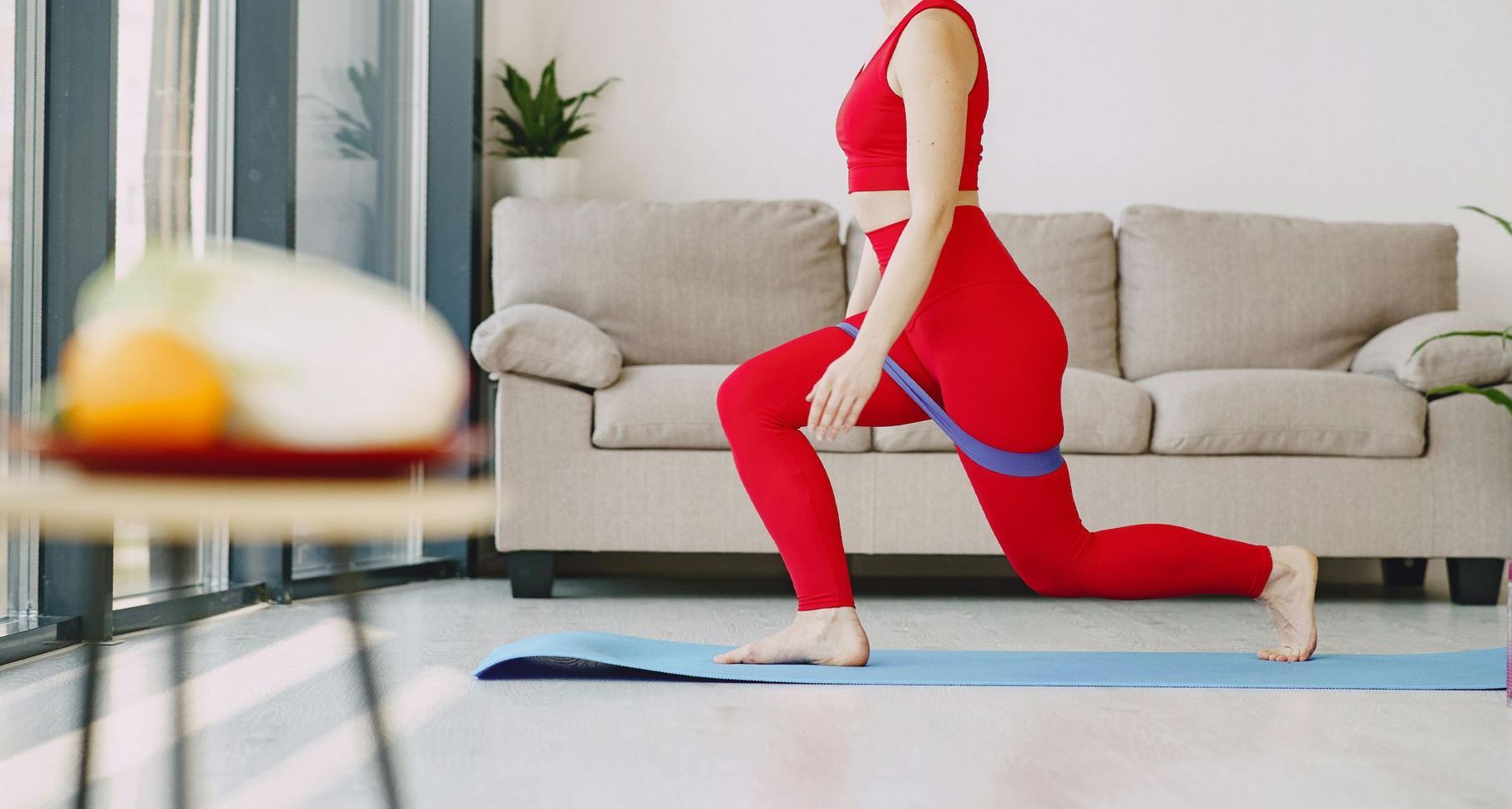 En kvinde laver udfald på en yogamåtte i en stue.