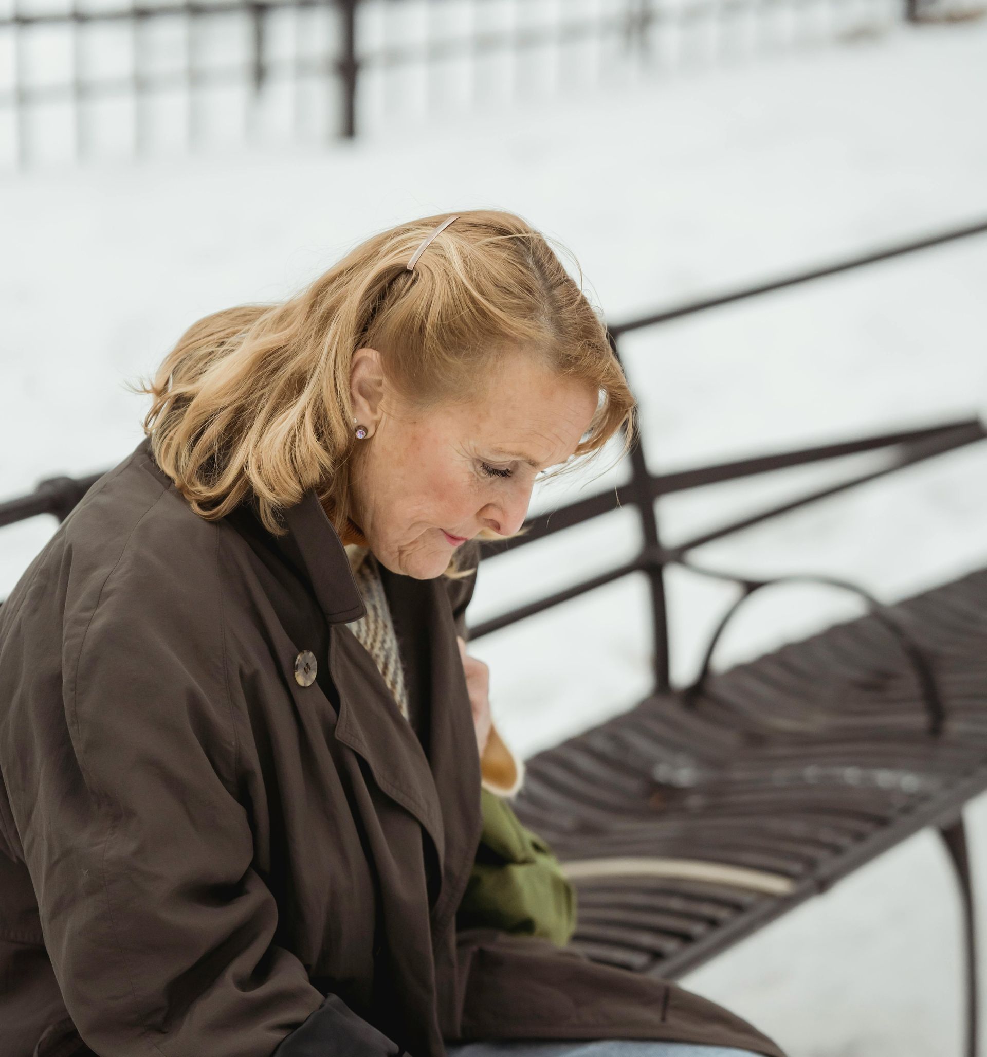 En kvinde sidder på en bænk i sneen