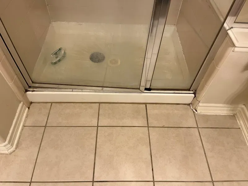 Shower stall with glass sliding doors, set on tiled floor.