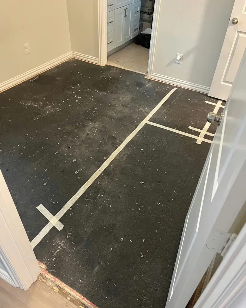 Dark floor with white tape markings, room with doorway and partial bathroom view.
