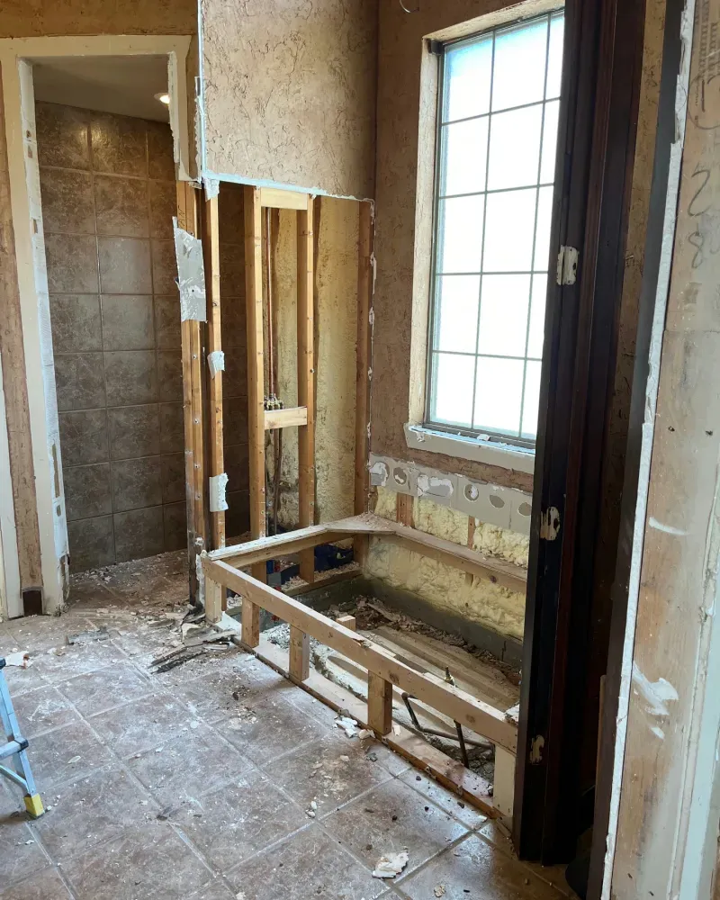 Bathroom renovation in progress, framing for a tub and shower area. Exposed studs and window.