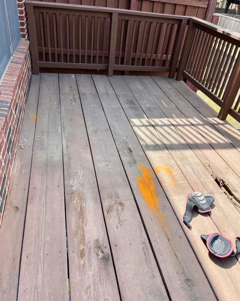 Wooden deck with brown railing and orange paint marks. Kneepads sit on the right.