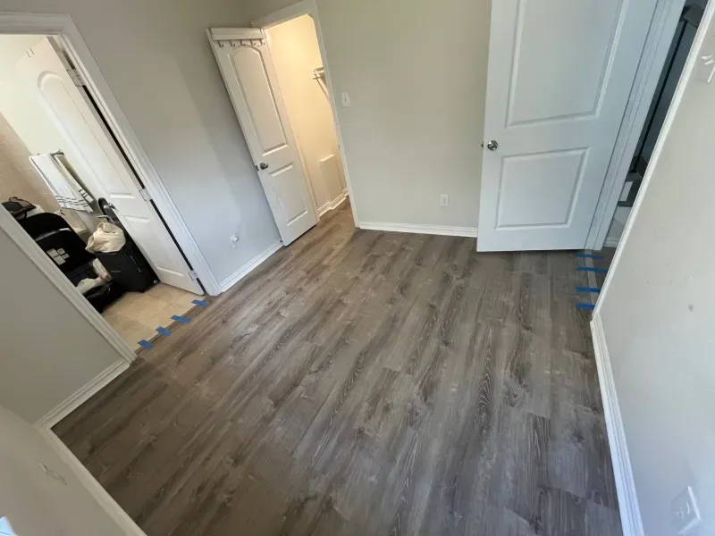 Newly installed wood-look flooring in a room with white doors and neutral walls.