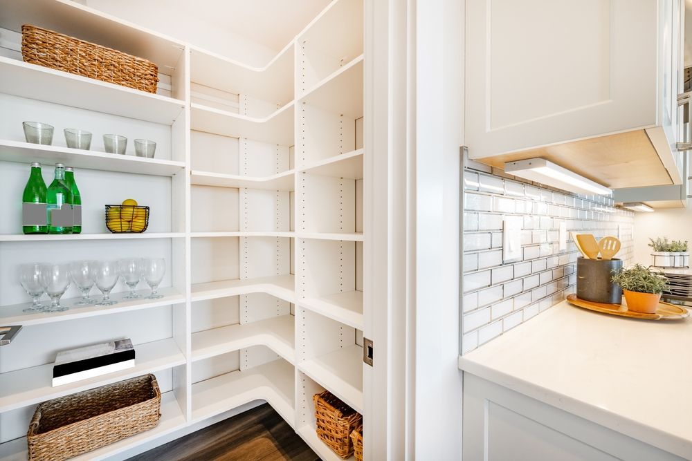 White pantry with multiple shelves; some items are on shelves.