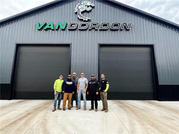 Group of men standing in front of a gray building with the name
