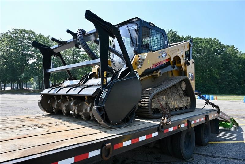 Yellow and black forestry mulcher on a trailer, ready for transport.