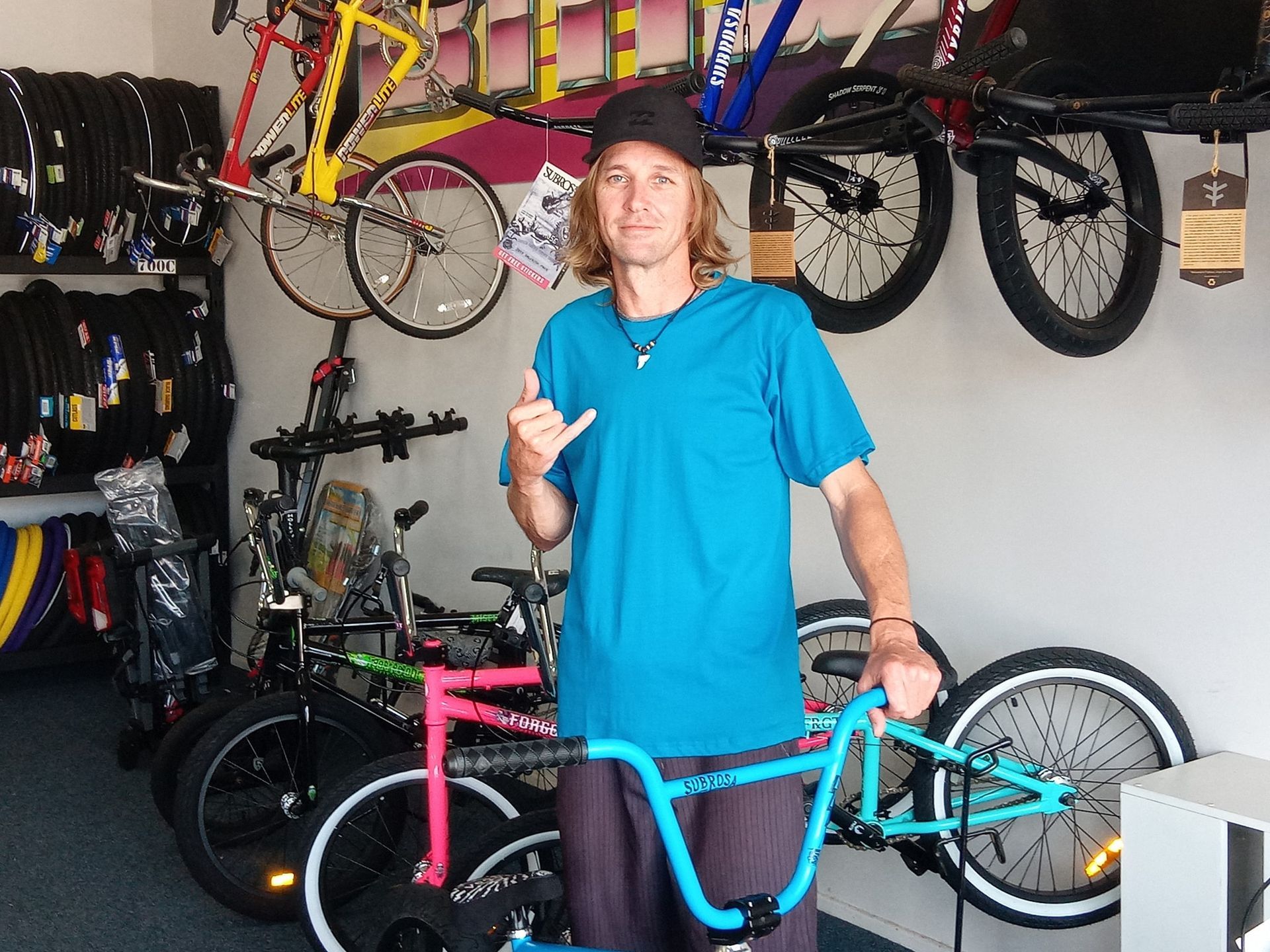 A man in a blue shirt is holding a bicycle and giving a thumbs up — Freedom Sports in Bundaberg Central, QLD