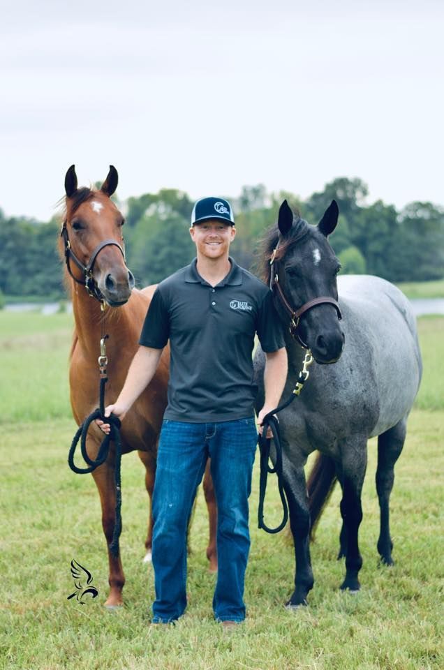 A man is standing next to two horses in a field.