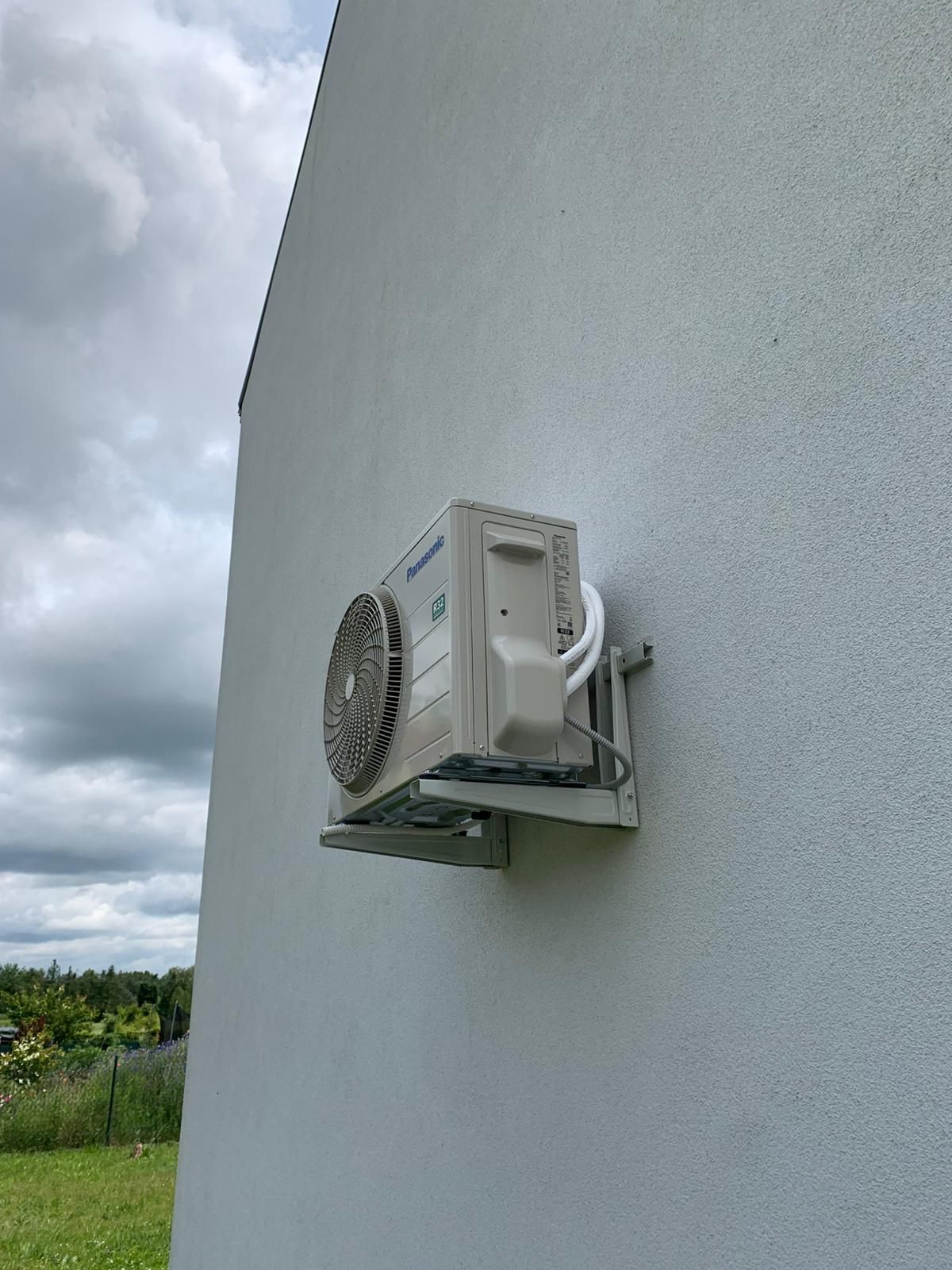 Biały klimatyzator jest zamontowany na ścianie budynku.