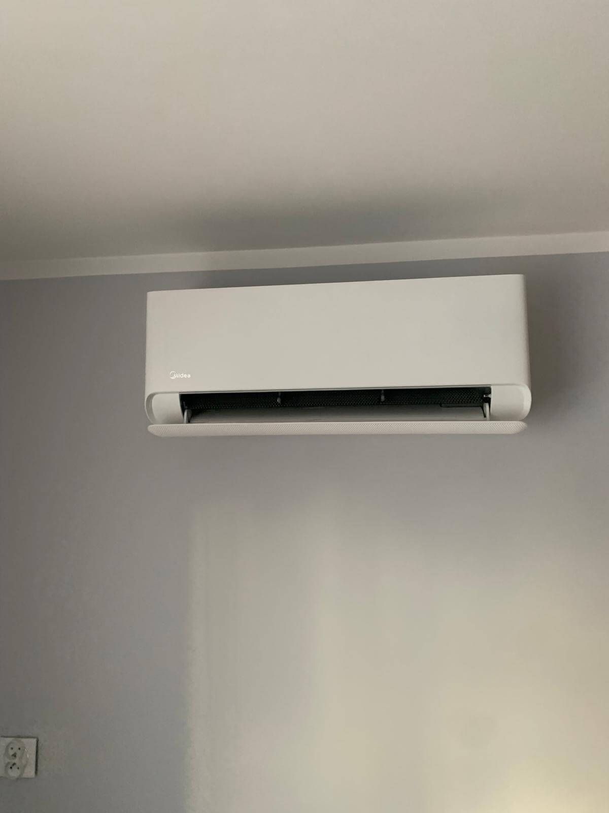 W pokoju pod sufitem wisi biała klimatyzacja.