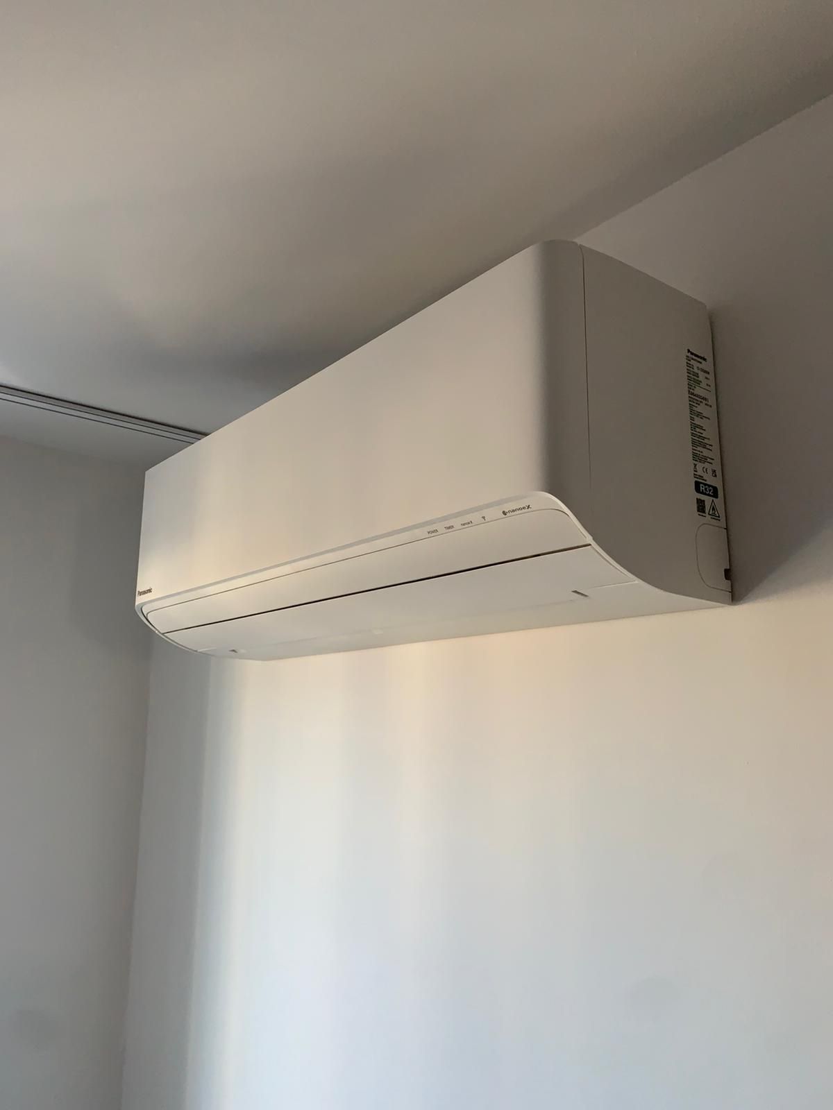 W pokoju pod sufitem wisi biała klimatyzacja panasonic