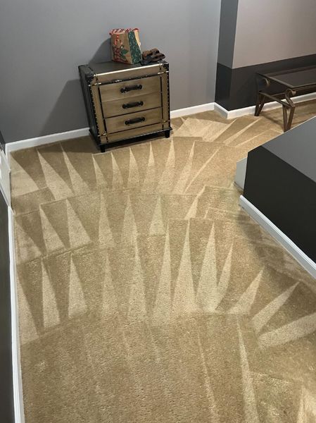 Beige carpet with geometric cleaning pattern, nightstand in the corner.