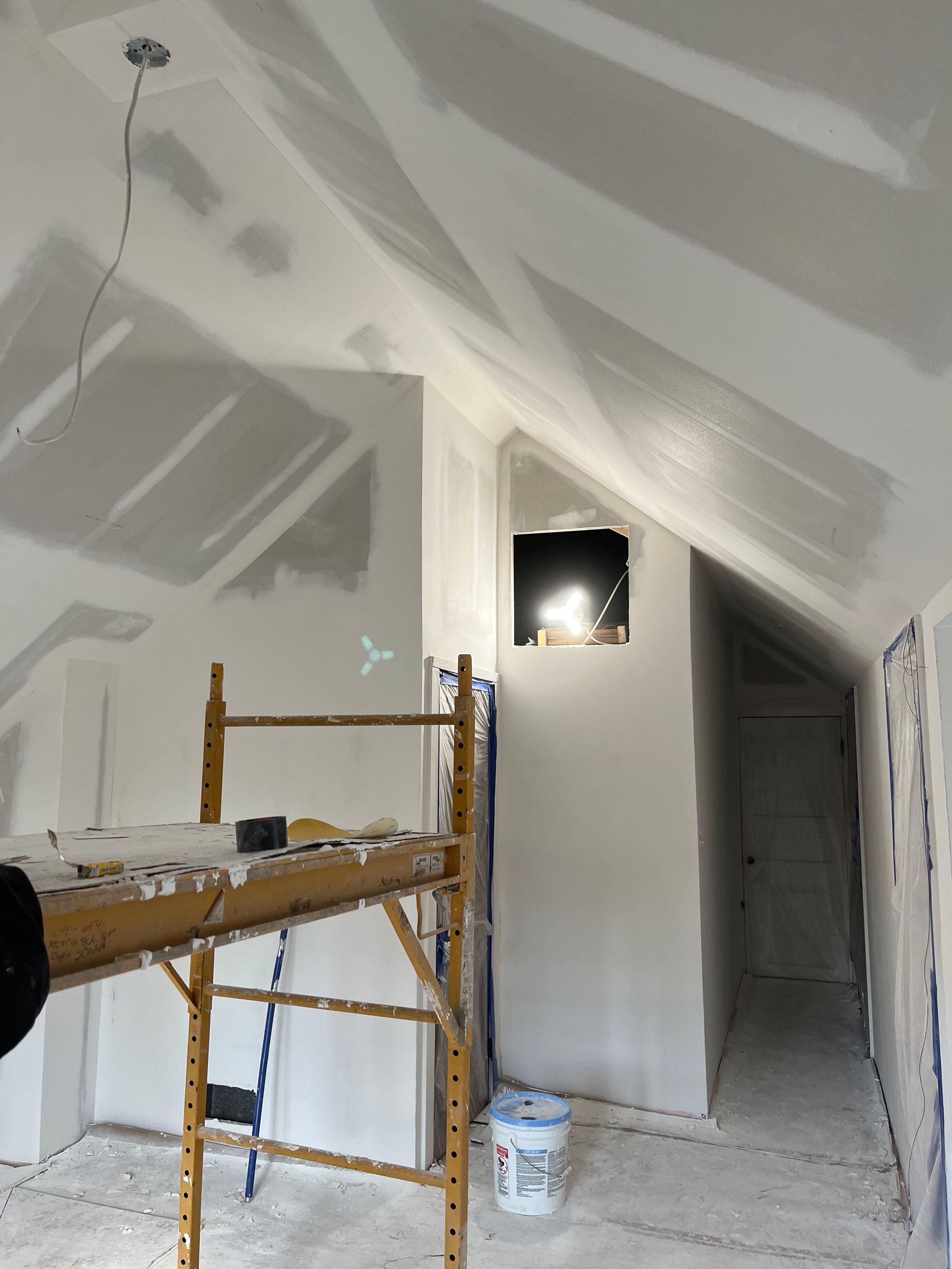 Person in overalls applying plaster to a wall with a trowel.
