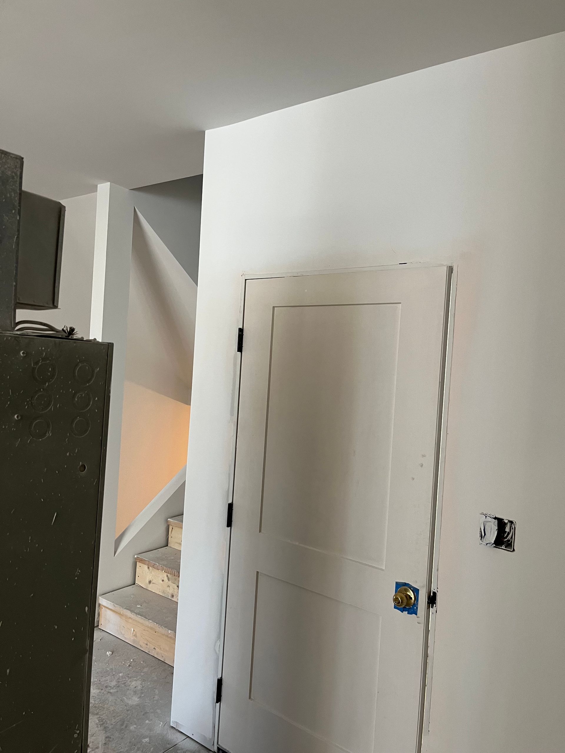 White-painted interior with a door, stairs, and part of a cabinet visible. The walls are mostly white.