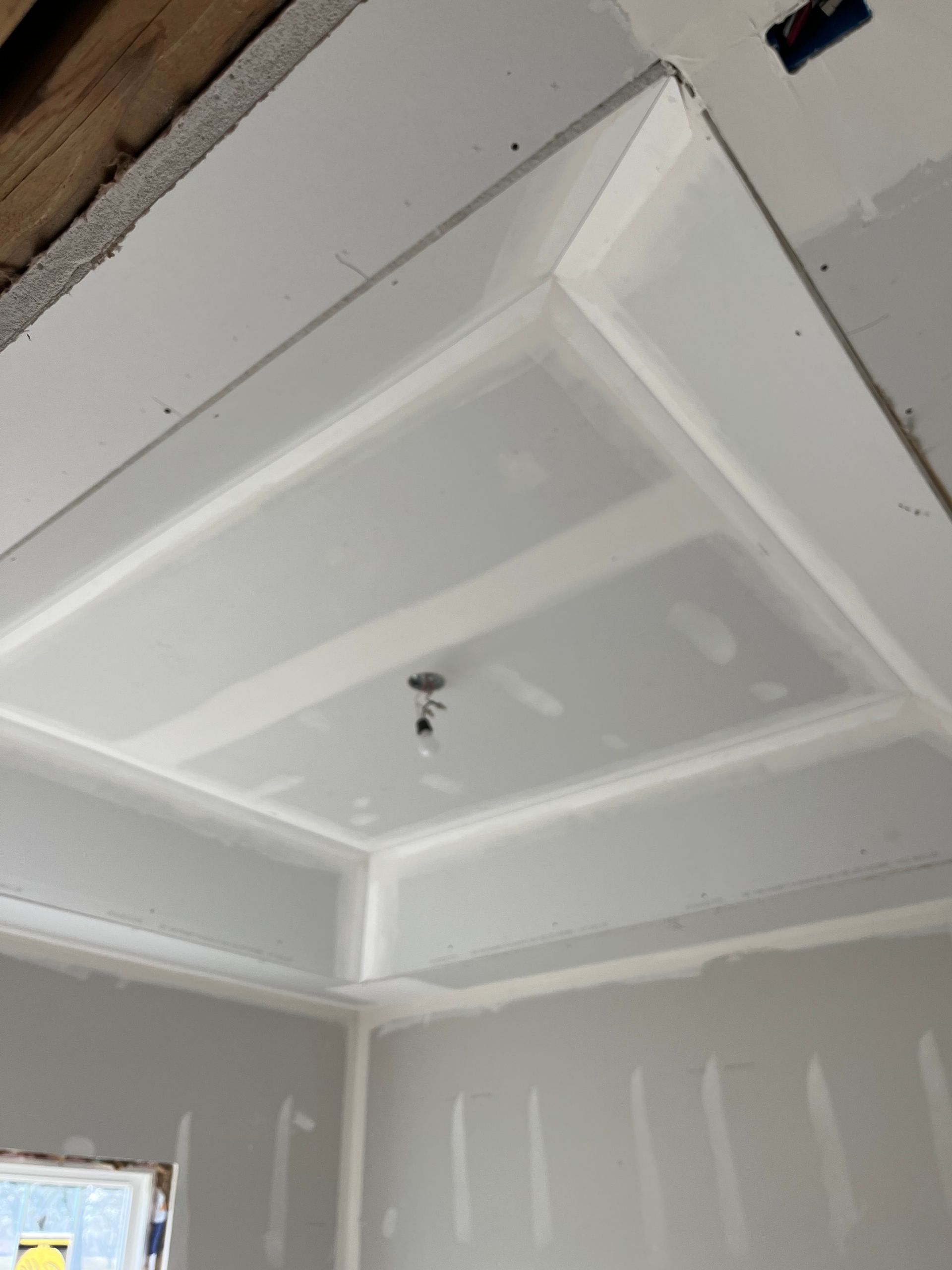 Finished drywall ceiling with a recessed square design; newly constructed room.