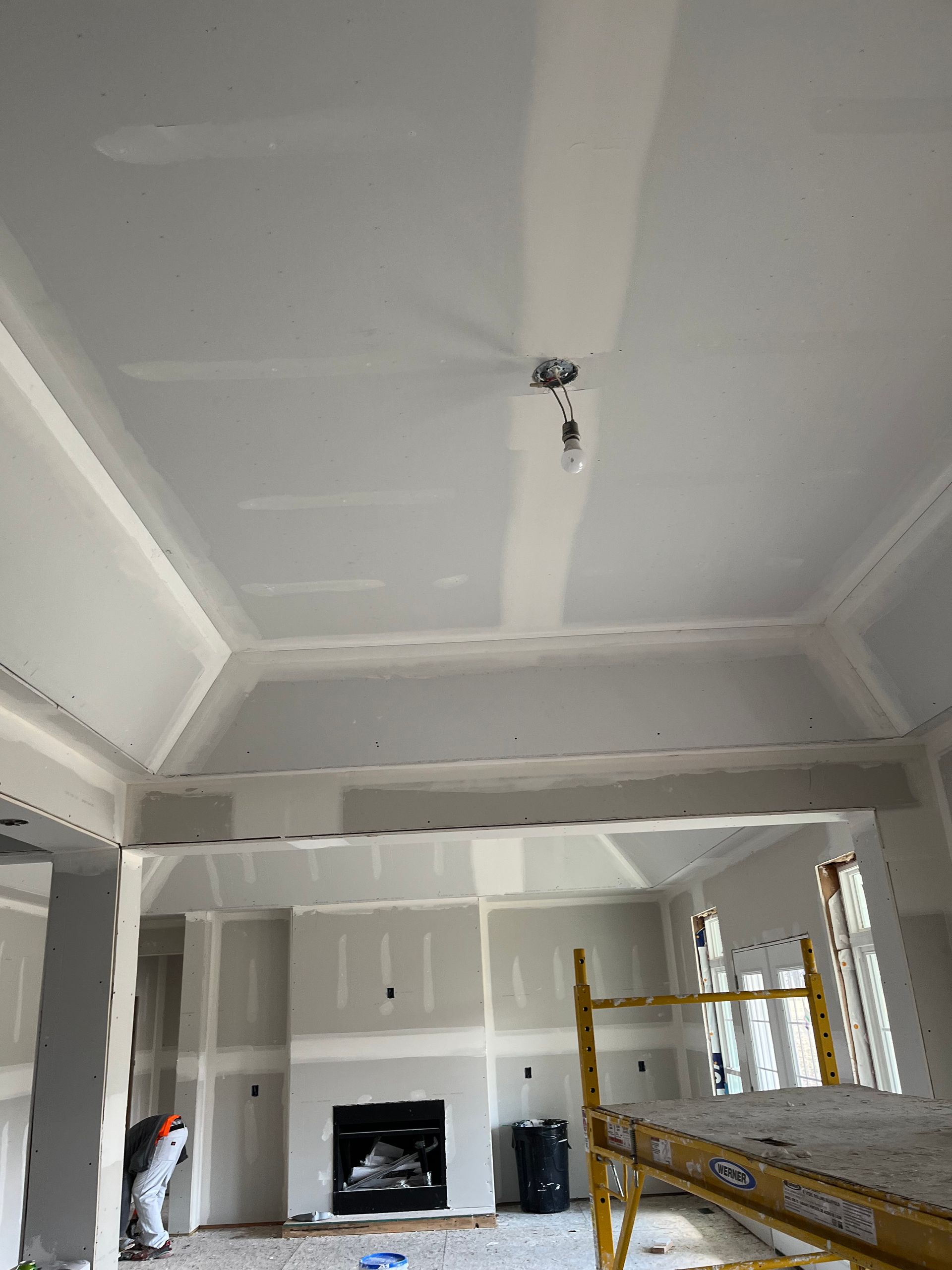 Interior room with unfinished drywall; fire place and scaffold present.