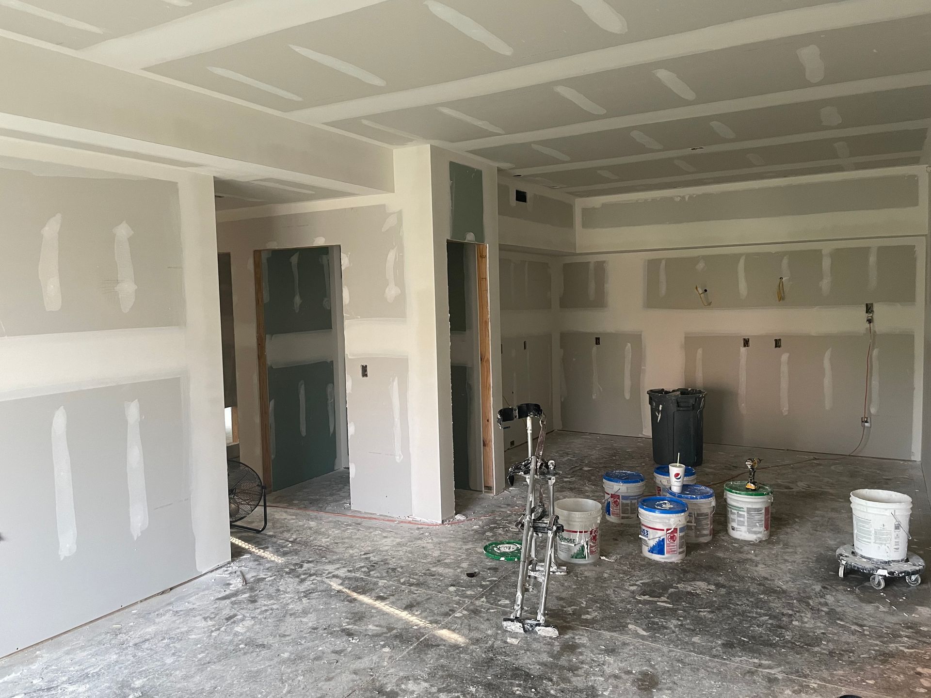A person is using a trowel to apply drywall mud to a wall.