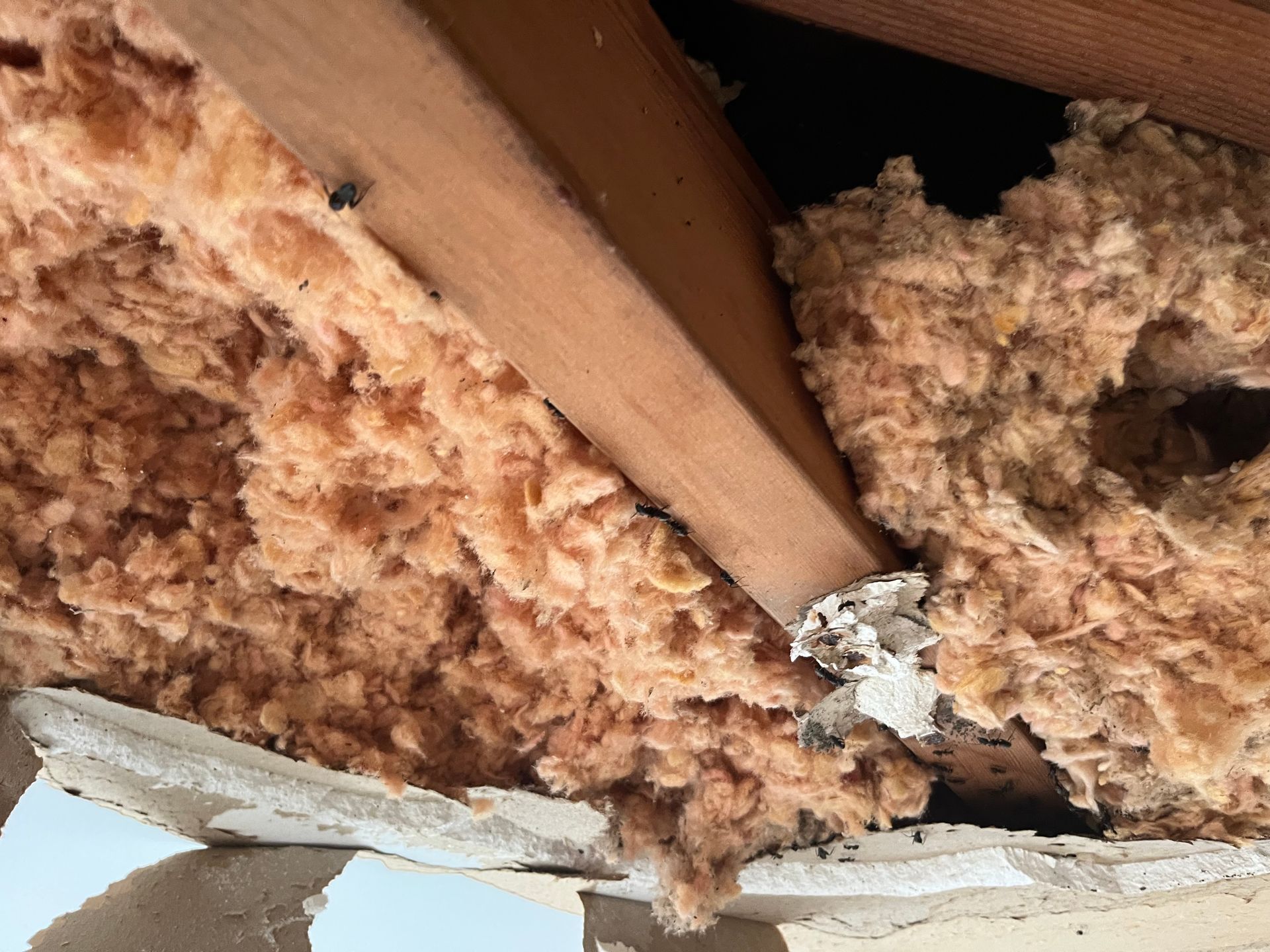 Person in overalls and gloves using a putty knife to apply joint compound to drywall.