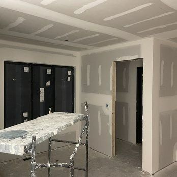 Interior under construction with drywall on walls and ceiling; scaffolding in front.