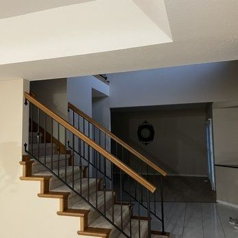 Staircase with wooden steps and railing, black iron balusters, and entryway into a home.
