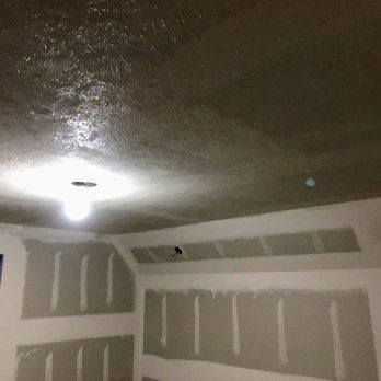 Interior view of a room with unfinished drywall and a wet-looking ceiling around a light fixture.