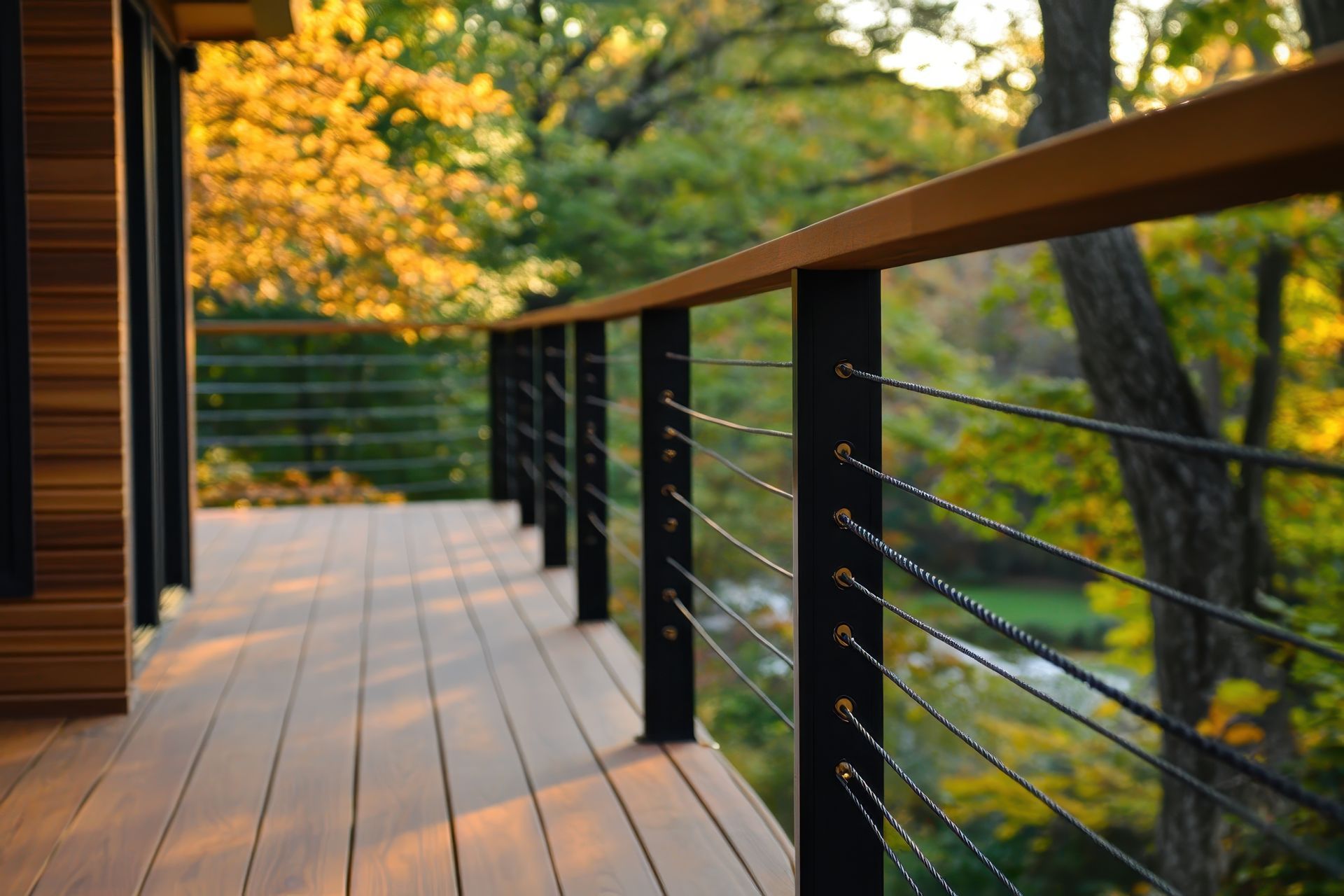 A wooden deck with a black railing and trees in the background.