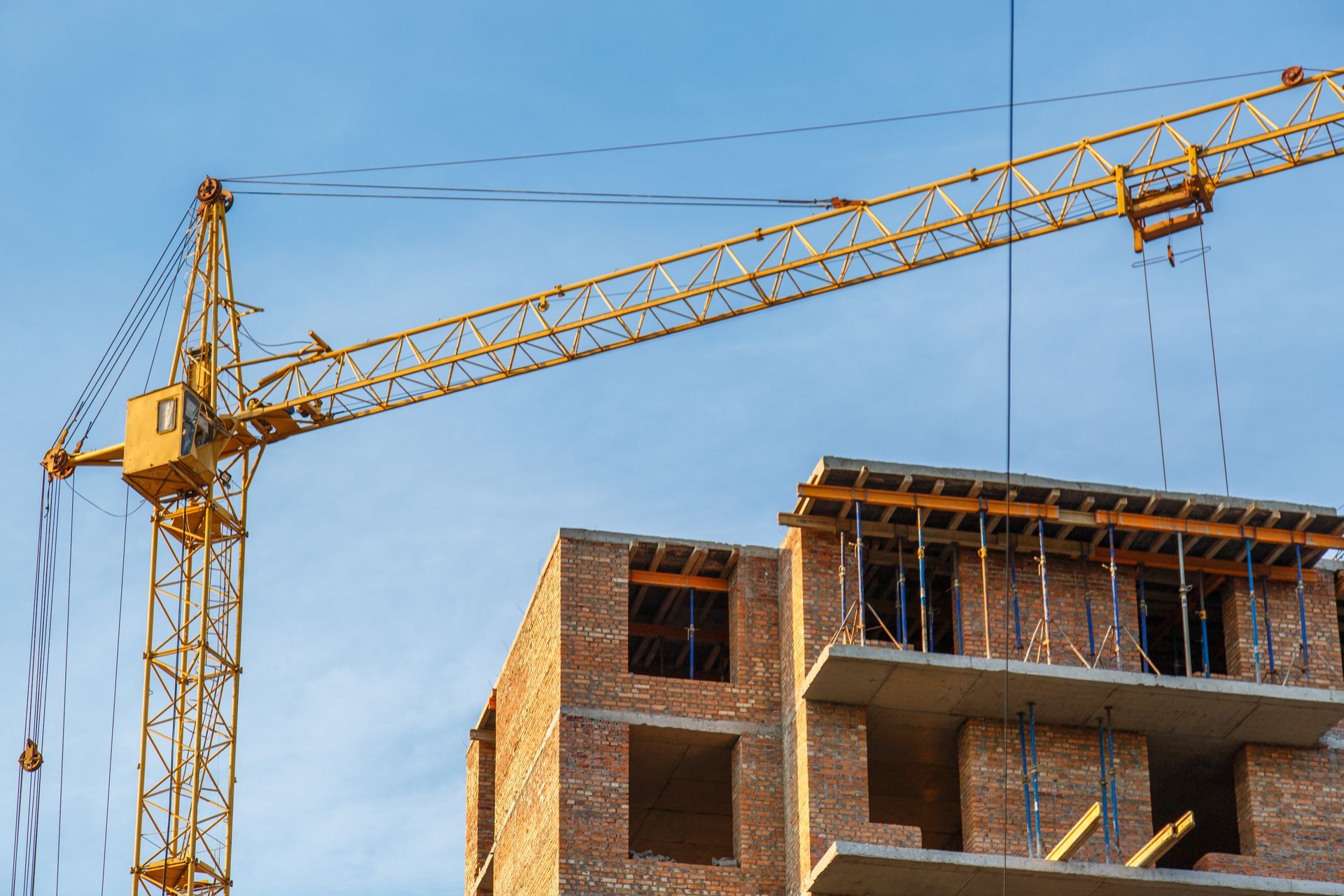 A yellow crane is working on a building under construction.