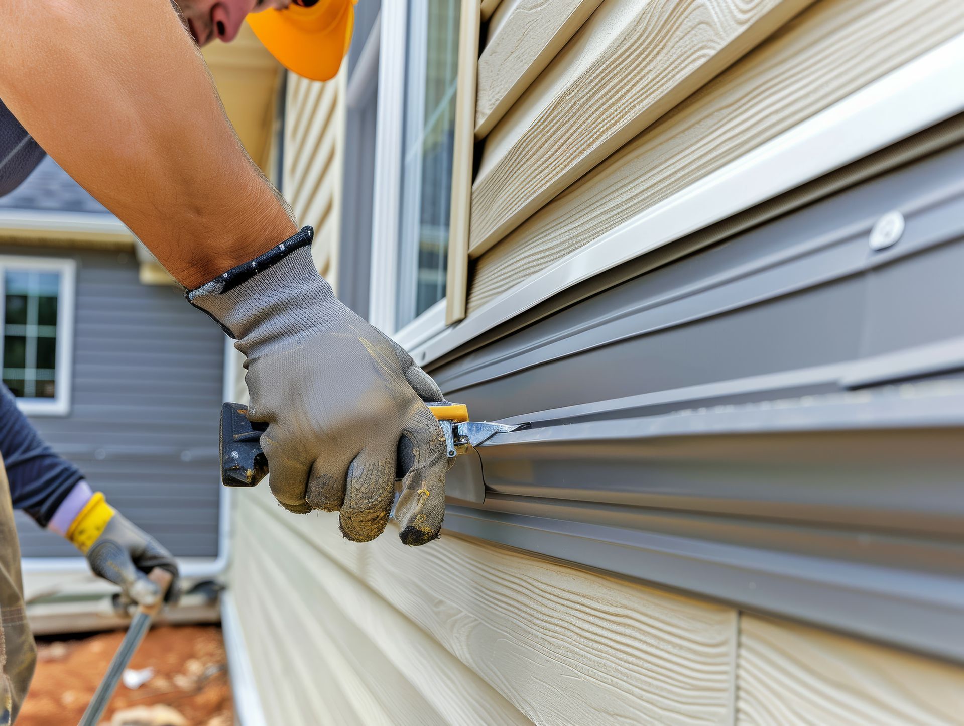 A man is installing siding on the side of a house.