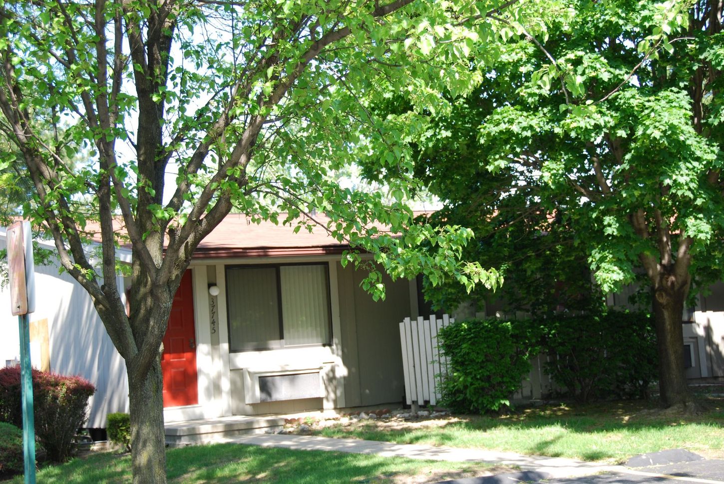 A small house with a red door is surrounded by trees
