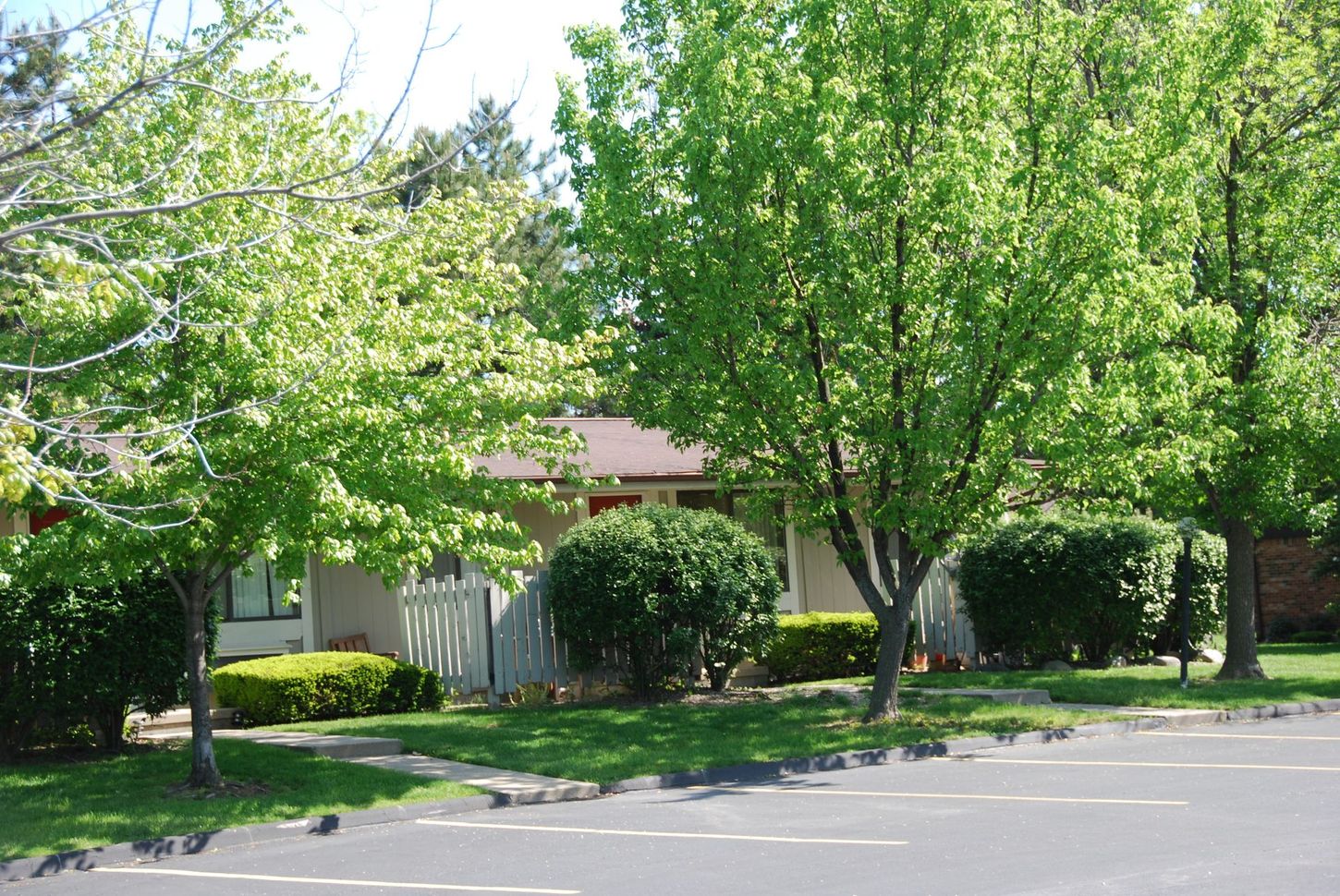 A house with a red roof is surrounded by trees and bushes