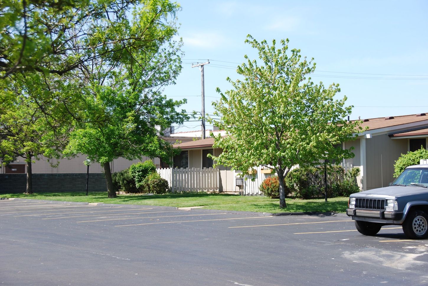 A jeep is parked in a parking lot in front of a house