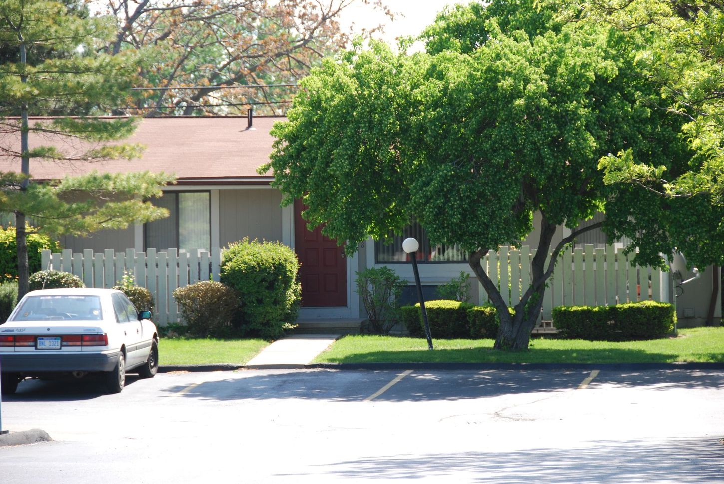 A white car is parked in front of a house