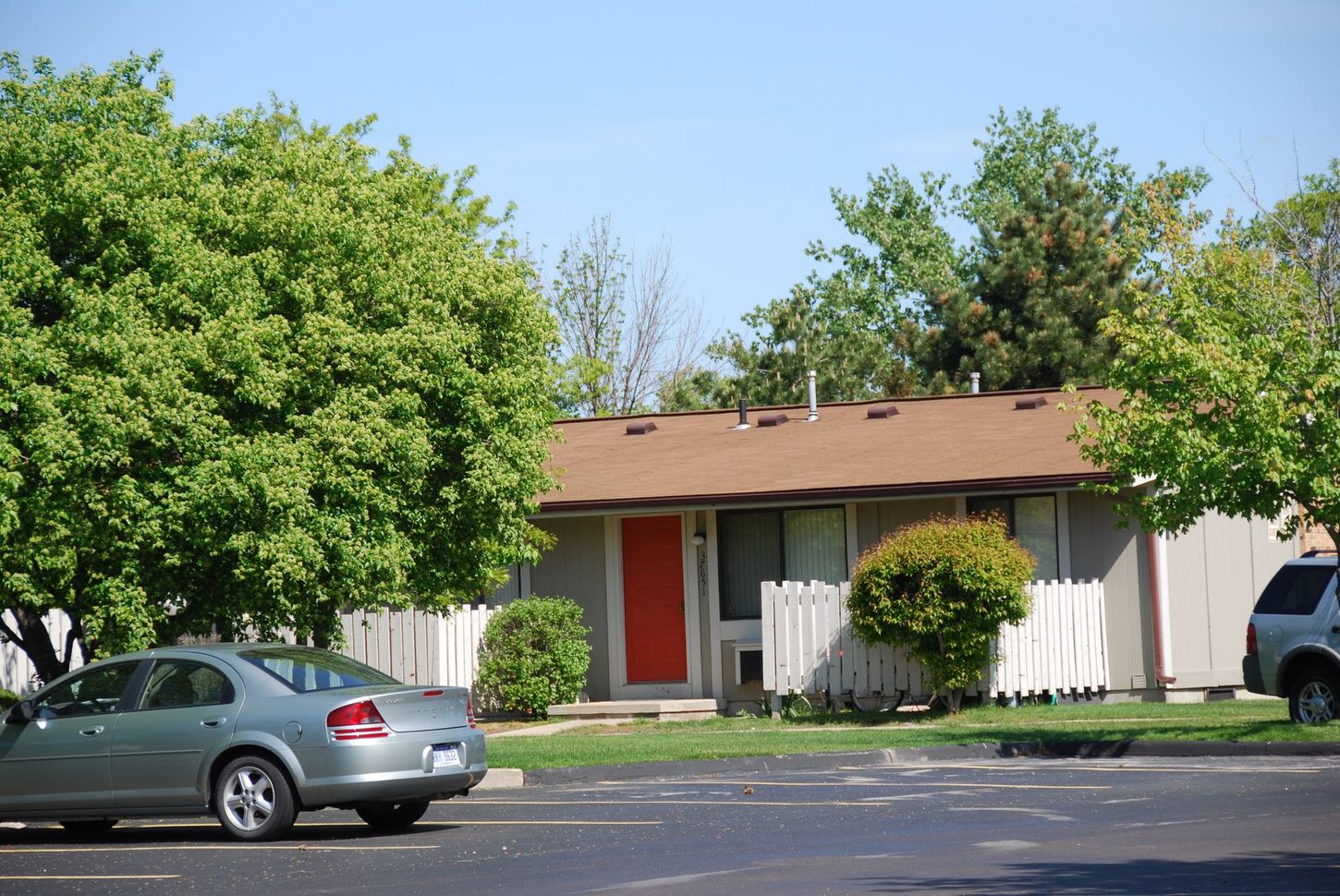 A car is parked in front of a house with a red door
