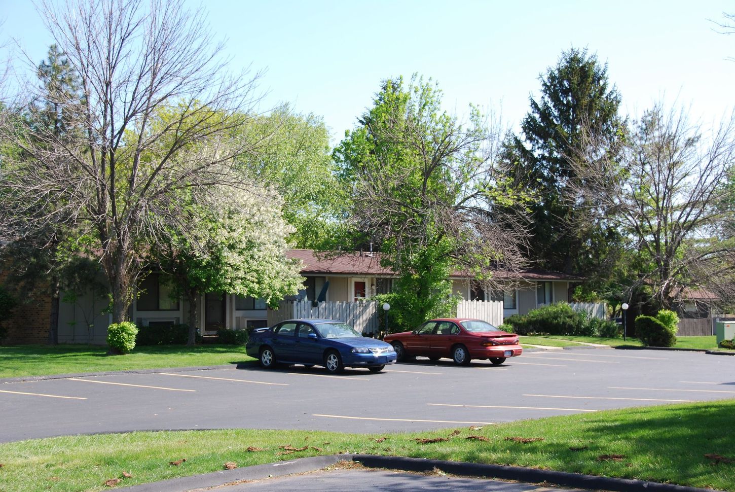 Two cars are parked on the side of the road in front of a house