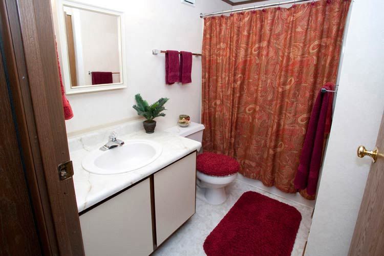 A bathroom with a sink a toilet and a red shower curtain