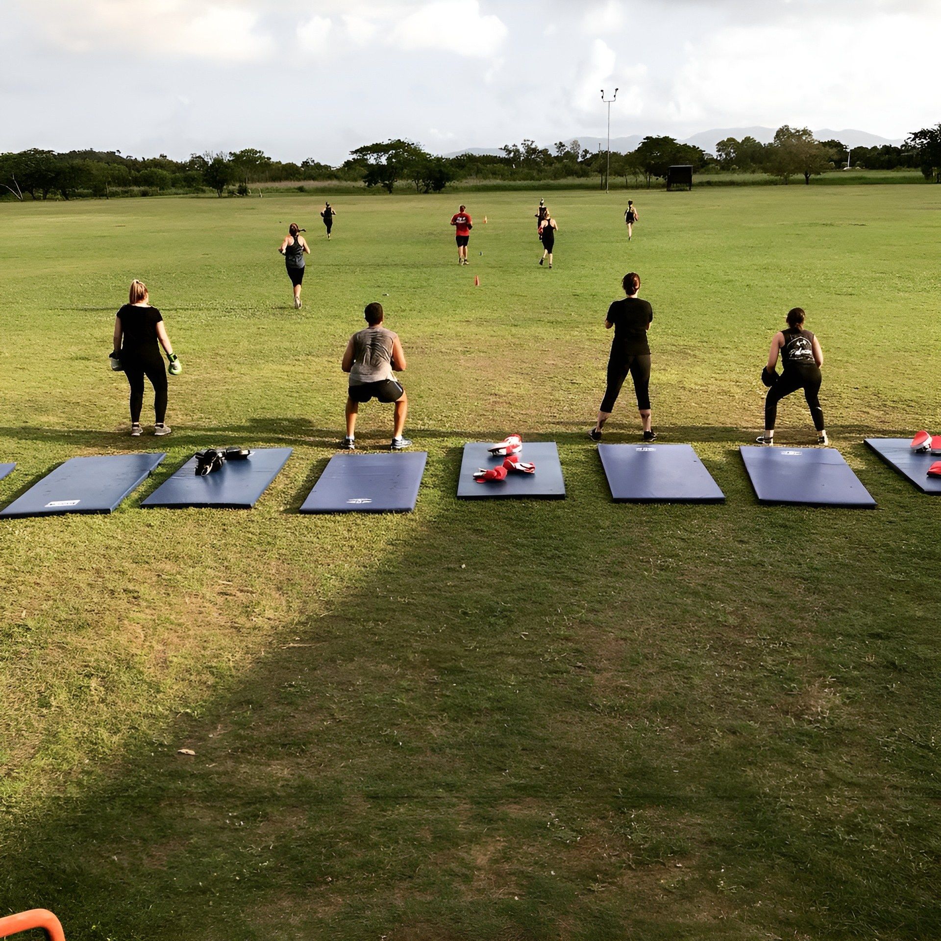 A Group of People Are Doing Exercises in a Grassy Field — Health First Townsville In Townsville, QLD